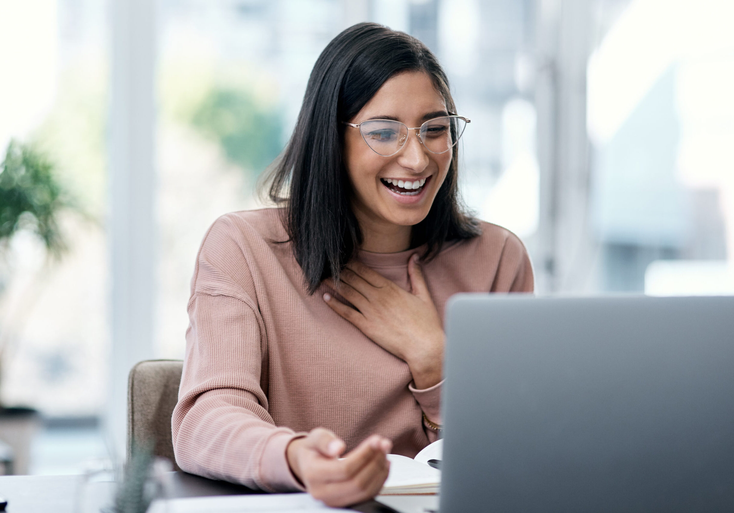 Shot of a young woman using a laptop and looking surprised while working from home