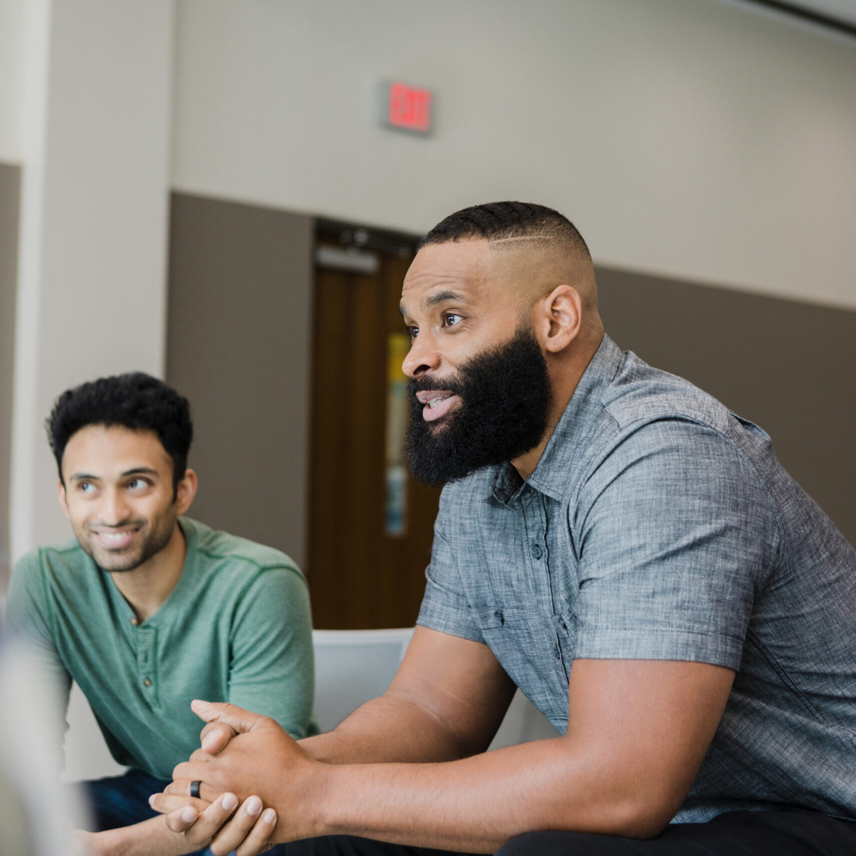 Three diverse men smile during group therapy.