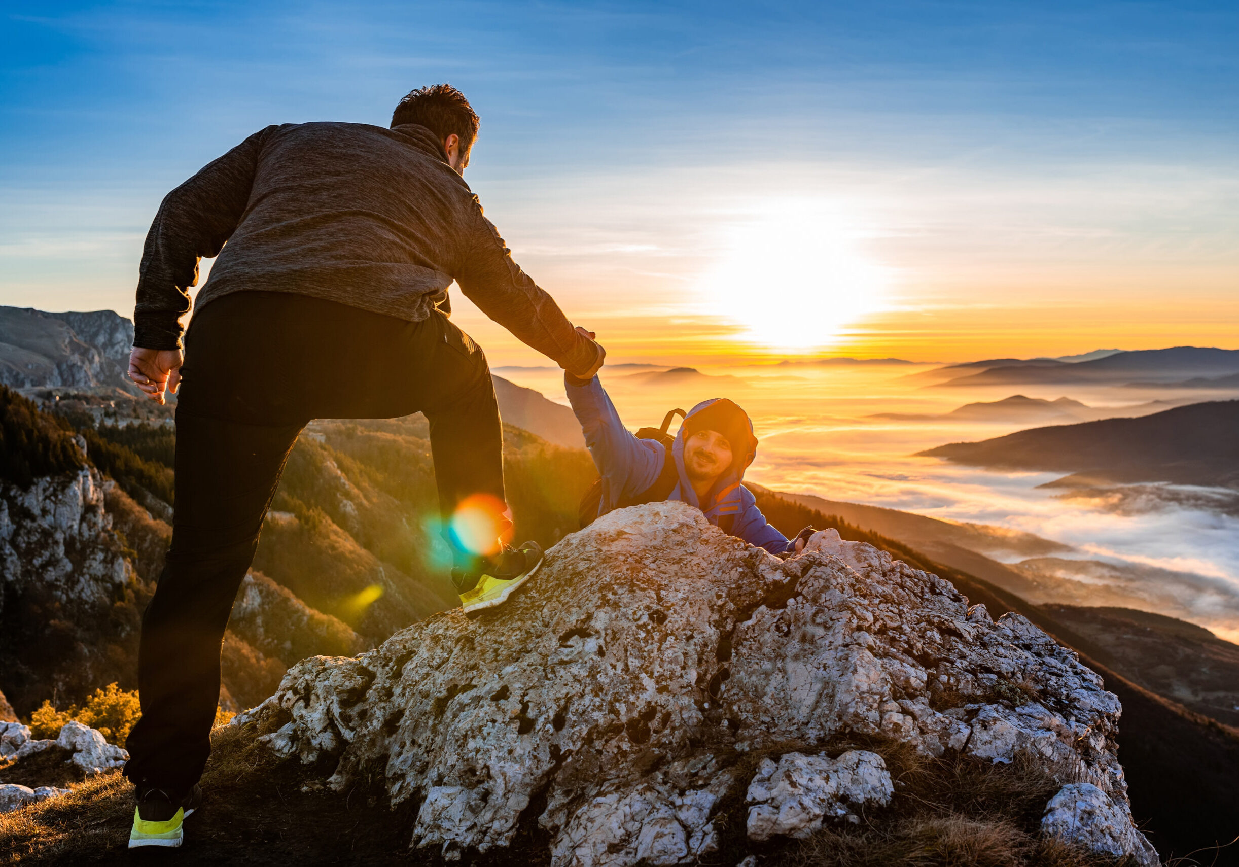 Hiking team people helping each other friend giving a helping hand while climbing up on the mountain rock adventure travel concept of friendship support trust teamwork success. High quality photo