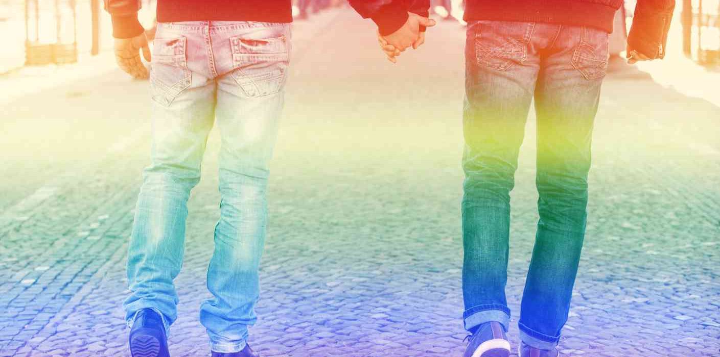 two men walking and holding hands with the rainbow colors for gay pride LGBTQIA+ Addiction Treatment Center