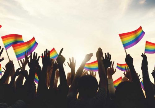 A crowd with LGBT rainbow flags Breathe Signature Services LGBTQI